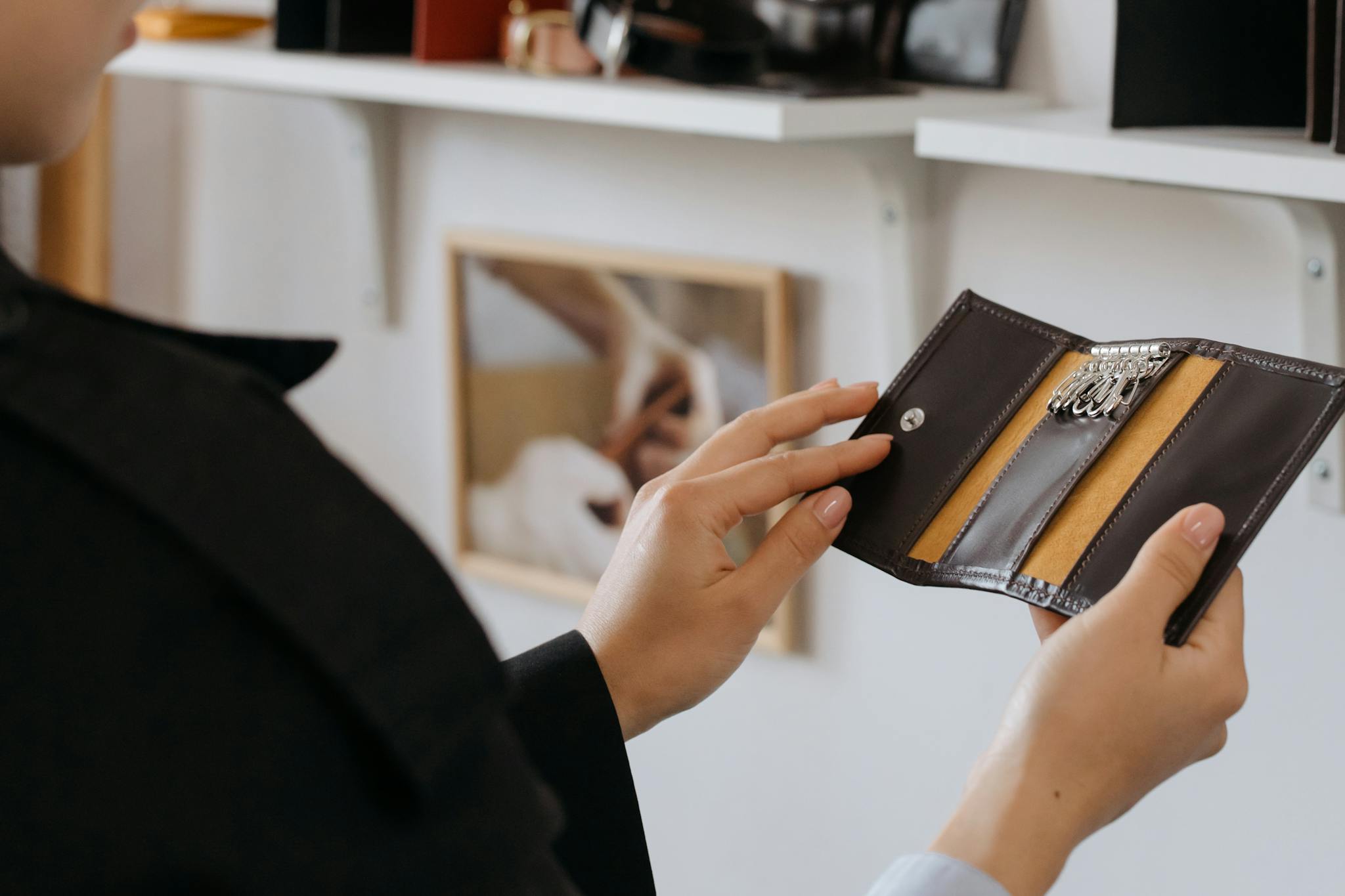 Close-up of hands holding a sleek leather keyholder indoors, showcasing design and craftsmanship.