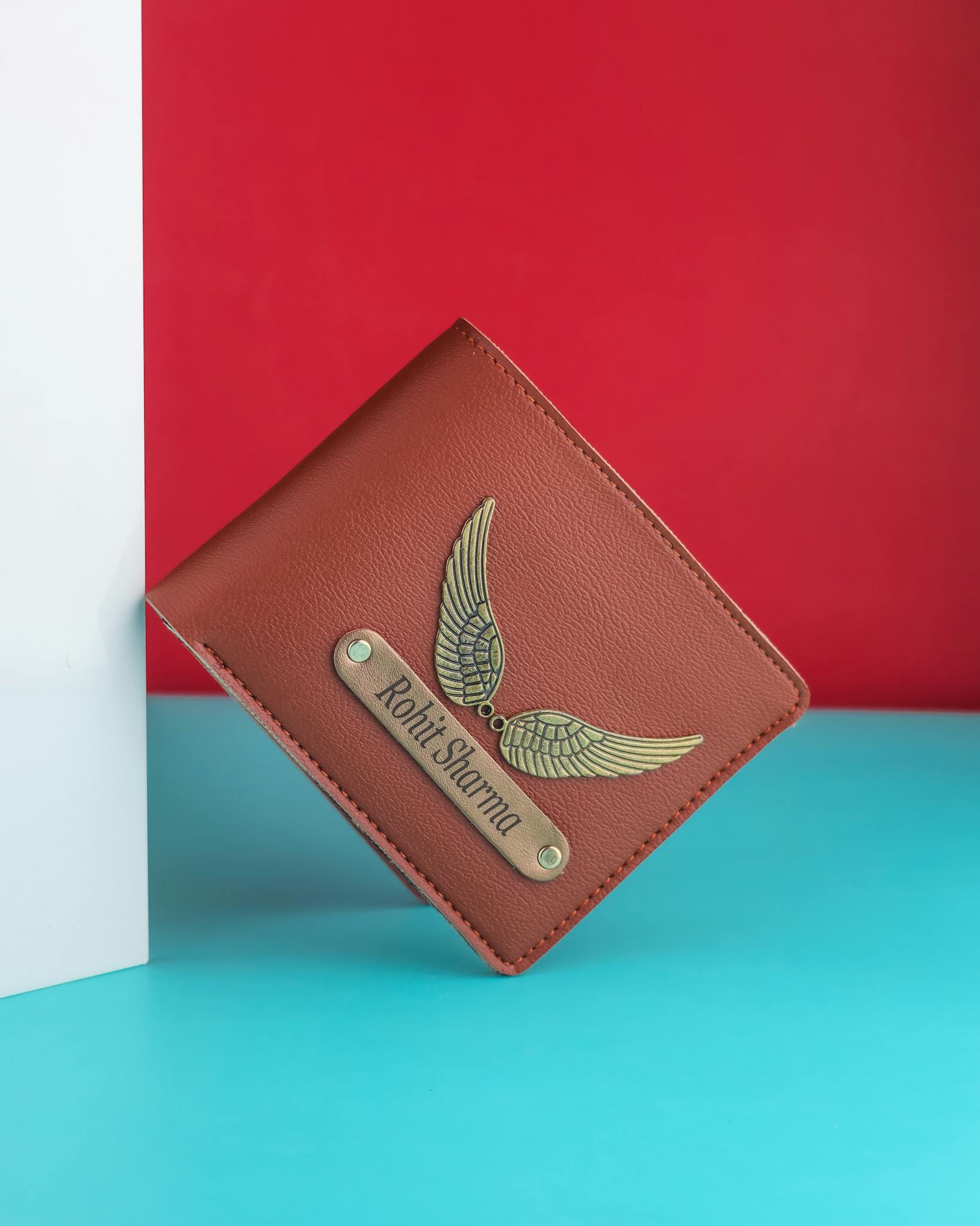 Stylish brown leather wallet featuring a metallic wing design and personalized nameplate.